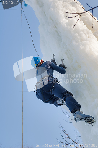 Image of Man climbs upward on ice climbing competition