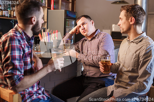 Image of The  friends drinking beer at counter in pub