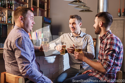 Image of Happy friends drinking beer at counter in pub