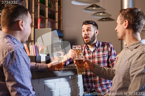 Image of Happy friends drinking beer at counter in pub