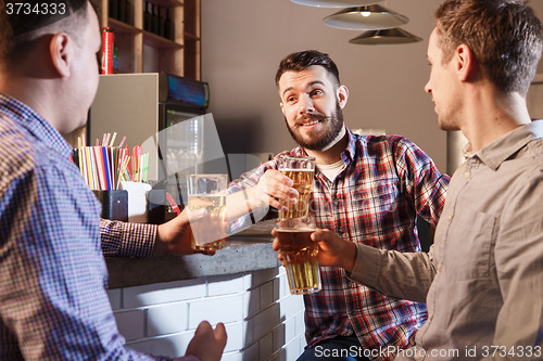 Image of Happy friends drinking beer at counter in pub