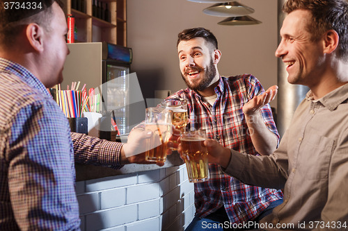 Image of Happy friends drinking beer at counter in pub