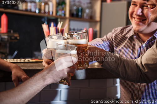 Image of Happy friends drinking beer at counter in pub