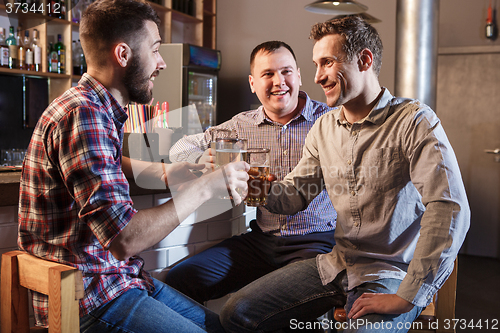 Image of Happy friends drinking beer at counter in pub