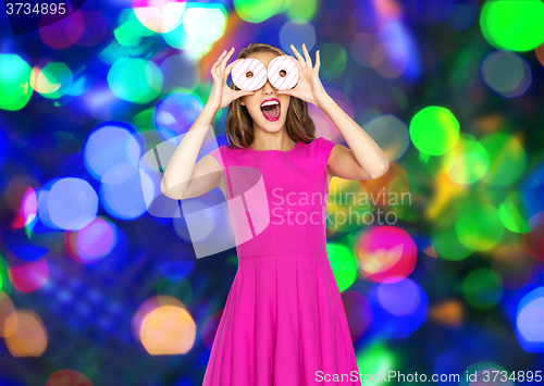 Image of happy woman or teen girl having fun with donuts