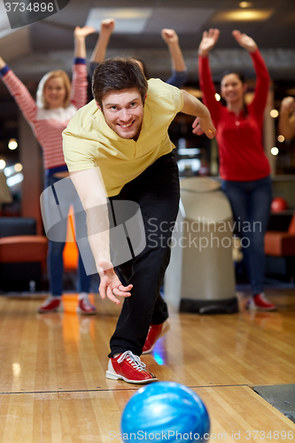 Image of happy young man throwing ball in bowling club