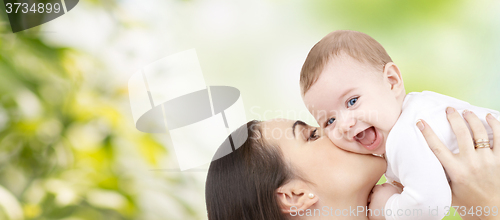 Image of happy mother kissing baby over green background