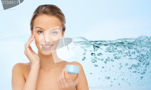 Image of smiling young woman applying cream to her face