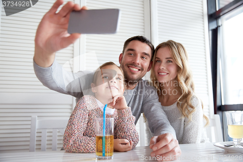 Image of happy family taking selfie at restaurant