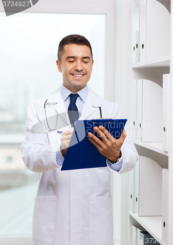 Image of happy doctor with clipboard in medical office