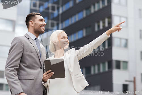 Image of smiling businessmen with tablet pc outdoors