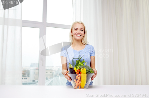 Image of smiling young woman cooking vegetables at home