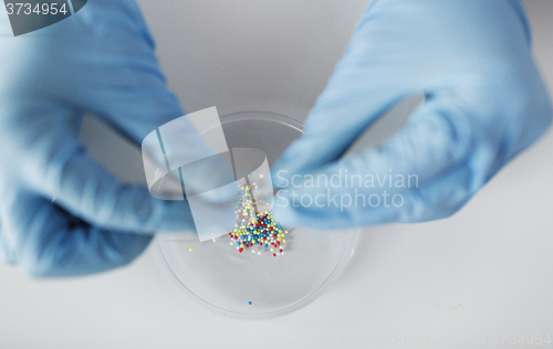 Image of close up of scientist hands holding pill in lab