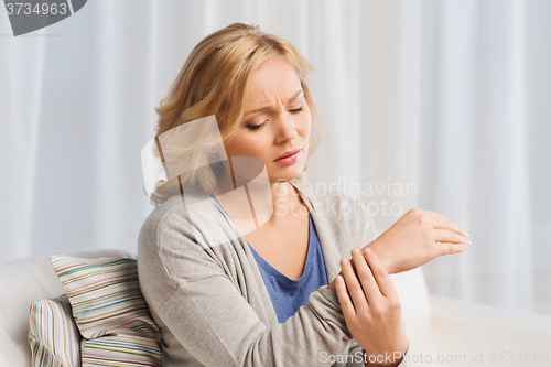 Image of unhappy woman suffering from pain in hand at home