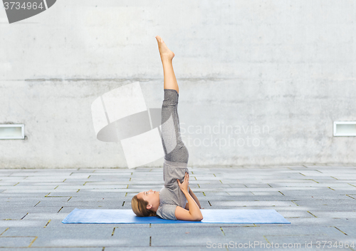 Image of woman making yoga in shoulderstand pose on mat