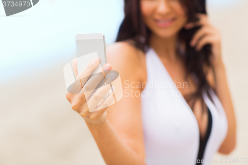 Image of young woman taking selfie with smartphone