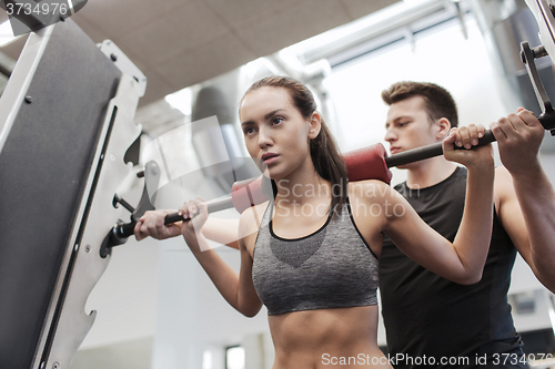 Image of man and woman with barbell flexing muscles in gym