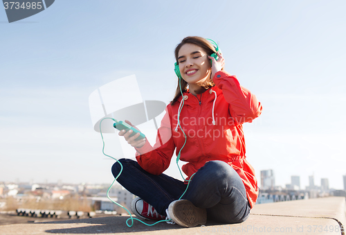 Image of happy young woman with smartphone and headphones