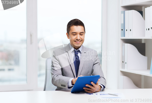 Image of smiling businessman with tablet pc in office