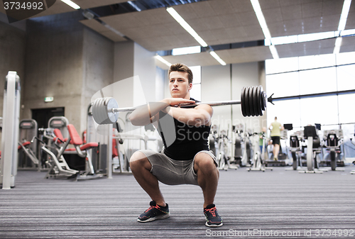 Image of young man flexing muscles with barbell in gym