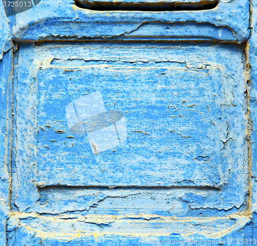 Image of stripped paint in the blue wood door and rusty nail