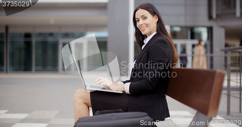 Image of Woman looking over with laptop on bench