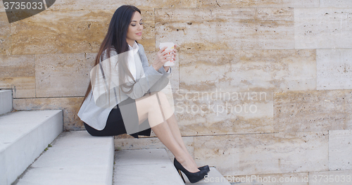 Image of Business woman looking at coffee cup