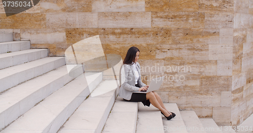 Image of Low angle view of woman using laptop outdoors