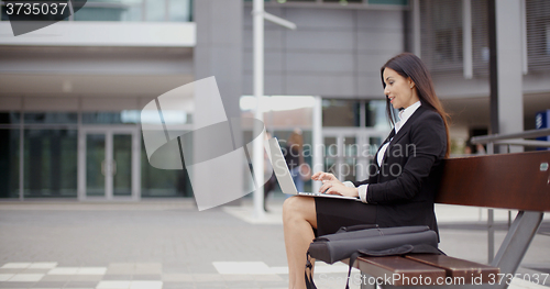 Image of Side view of woman alone with laptop on bench