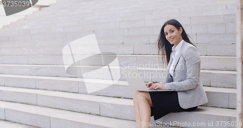 Image of Smiling woman using laptop on stairs