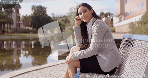 Image of Gorgeous business woman sitting on bench