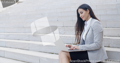 Image of Smiling woman using laptop on stairs