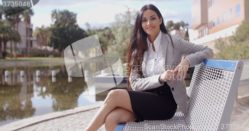 Image of Gorgeous business woman sitting on bench