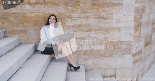 Image of Serious woman sitting on stairs outdoors