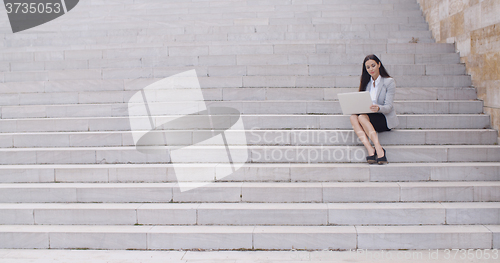 Image of Business woman with laptop on stairs