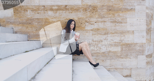Image of Business woman looking at coffee cup