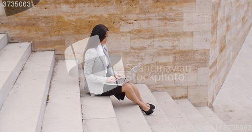 Image of Side view of woman using laptop on stairs