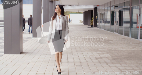 Image of Grinning optimistic professional woman walking