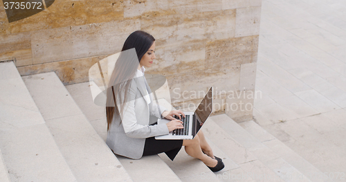 Image of Side view of woman using laptop on stairs