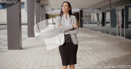 Image of Hopeful woman with folded arms near building