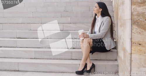 Image of Grinning woman on stairs drinking coffee