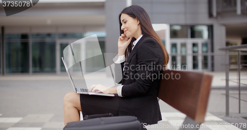 Image of Woman looking over with laptop on bench