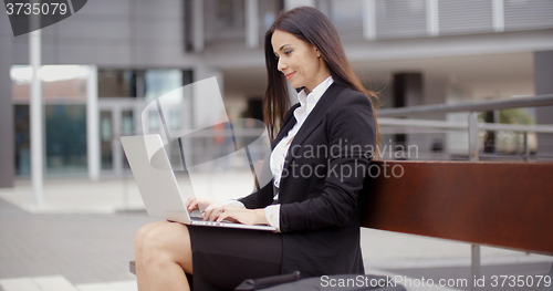 Image of Business woman alone with laptop on bench