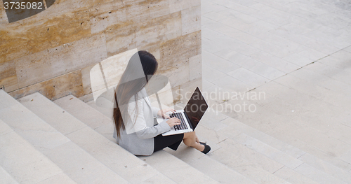 Image of High angle view of woman on laptop on stairs