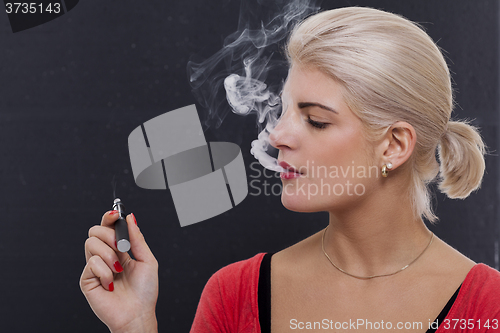 Image of Stylish blond woman smoking an e-cigarette