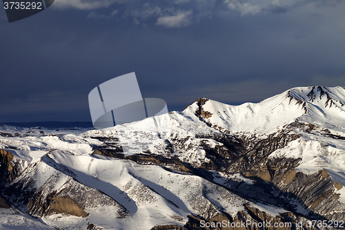 Image of Winter mountains at sun evening and dark clouds