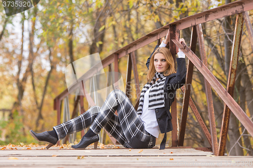 Image of Happy girl sitting on a bridge in the forest