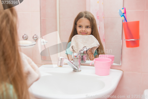 Image of Happy girl wipes her wet face towel in the bathroom