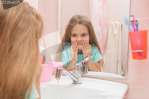 Image of Six year old girl washes her mouth after brushing your teeth in the bathroom