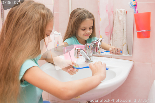 Image of Girl rinse the toothbrush under running tap water
